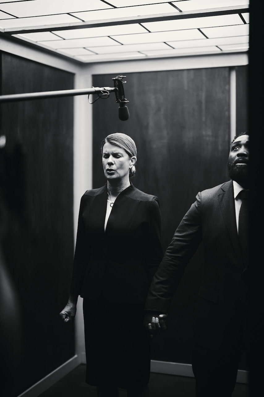 The two leads in character beneath the boom mic